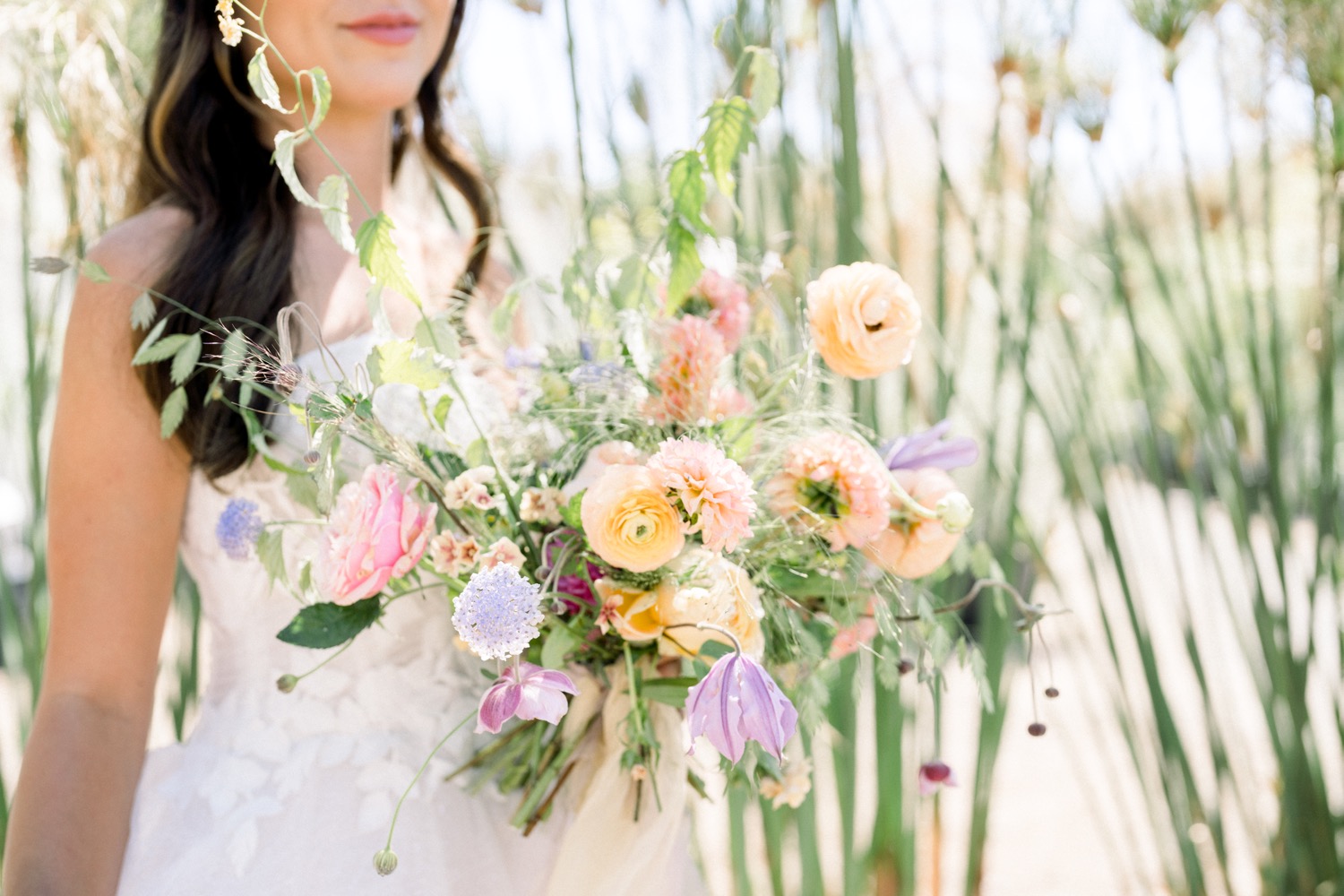 Close-up shot of a stunning bride posing next to vibrant colored flowers, captured by Pattengale Photography