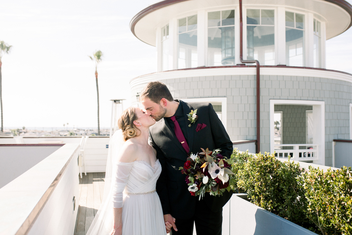 Bride and groom sharing a kiss, with a breathtaking view of the lighthouse behind them, taken by Pattengale Photography