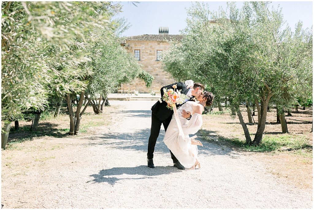 Sunstone Winery Wedding with Bride in a custom Berta Wedding Dress & Groom kissing in olive grove