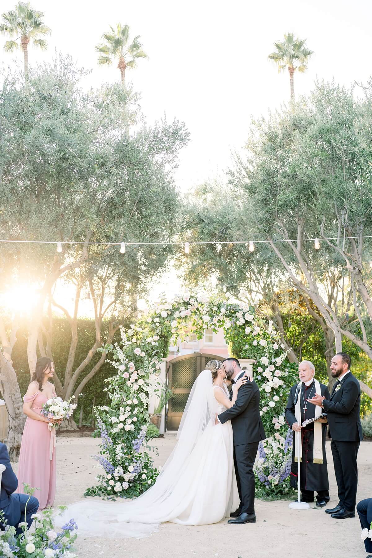 Olive grove outdoor wedding ceremony in Southern California with floral arch and black tie wedding guests captured by award-winning SoCal wedding photographer Pattengale Photography